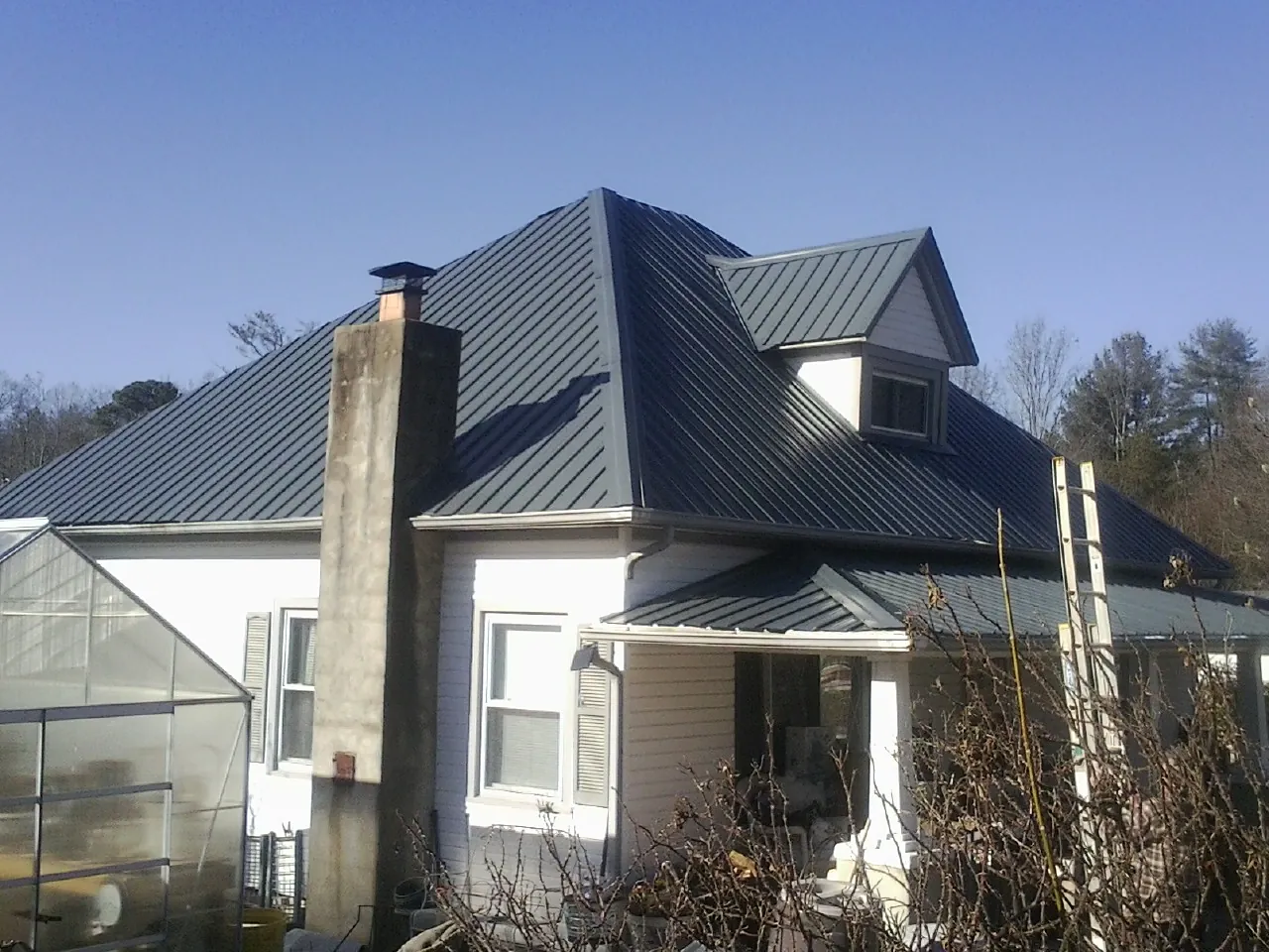 Dark blue standing seam metal roof on a white farmhouse with dormer — Slate & Tile Roof Repair by Roofing Brothers in Joelton