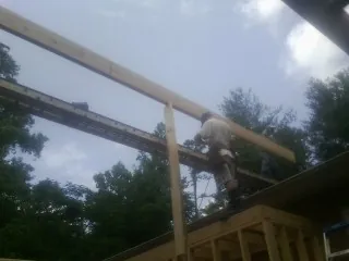 Carpenter setting a ridge beam over a new addition frame in Joelton