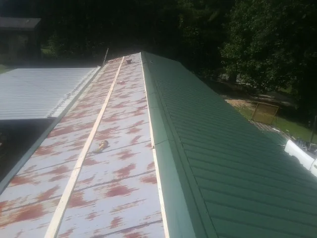 Old rusted panels beside newly installed green metal roofing — Wind Damage Roof Repair by Roofing Brothers in Joelton