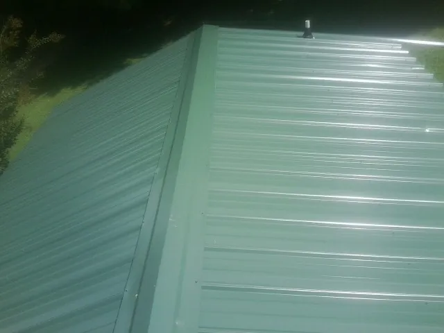 New green metal panels meeting at the ridge of a roof — Flat Roof Repair work by our crew in Joelton