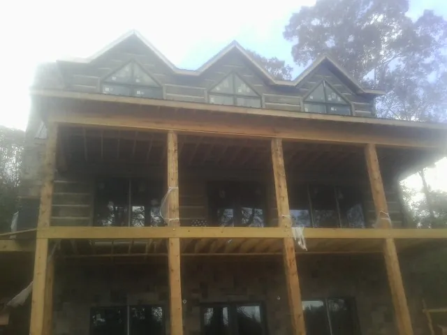 Dormers and porch framing on a large log home under construction — Roof Coating work by our crew in Joelton