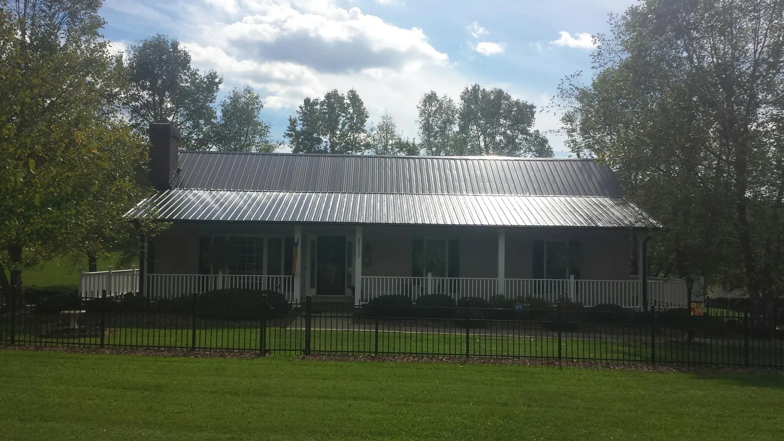 Gray metal roof on a brick ranch with a full width front porch — Gutter Guard Installation work by our crew in Joelton