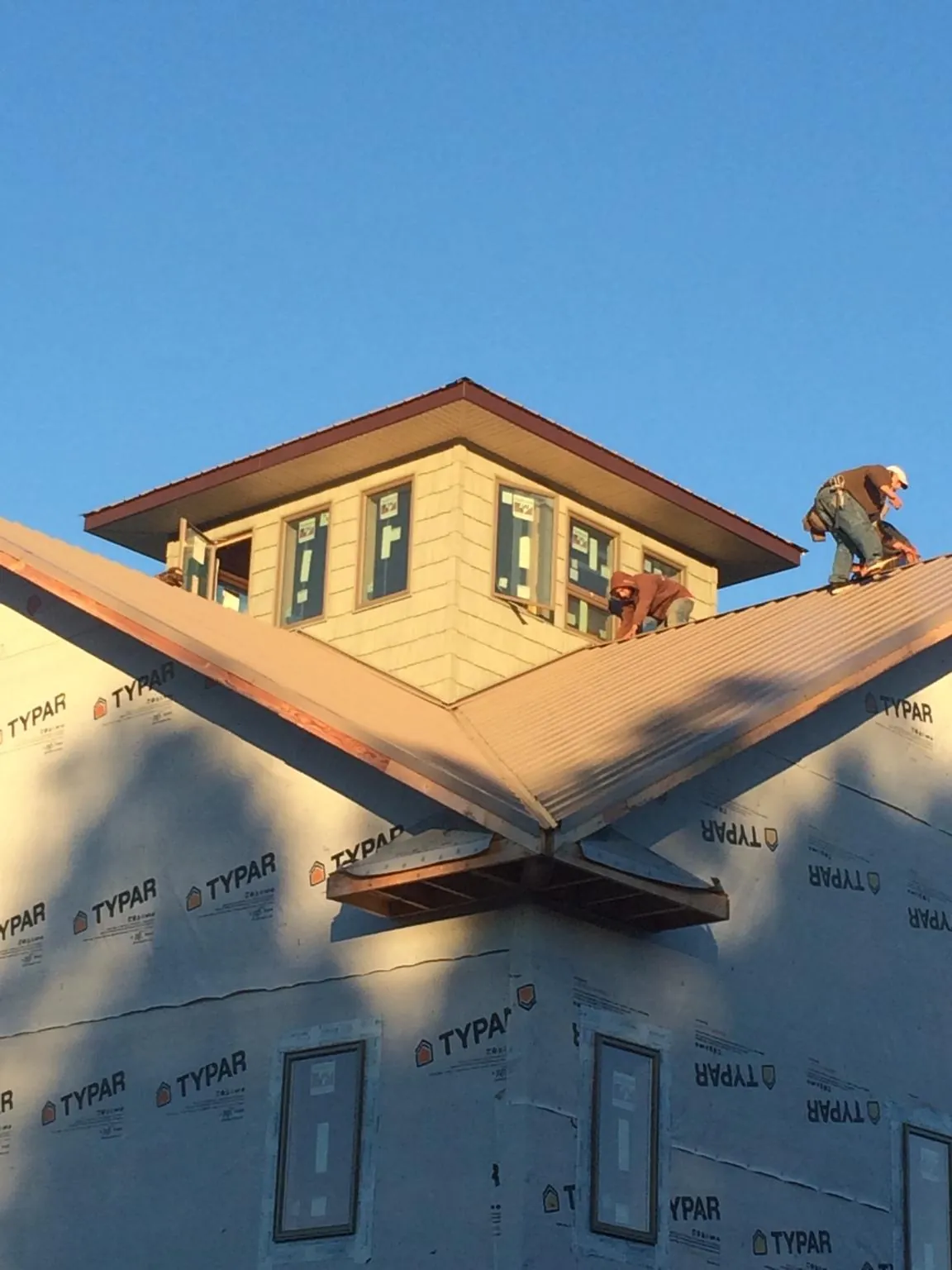 Roofers working around a rooftop cupola on a new metal roof at sunset — Roof Waterproofing in Joelton by Roofing Brothers